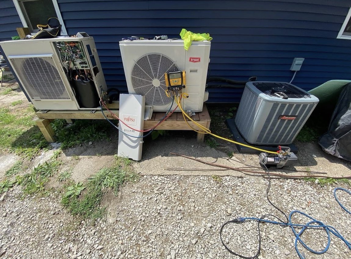 Our technician charging and testing a Bryant heat pump with gauges beside a Fujitsu ductless mini-split outdoor unit at a Niles, MI area home